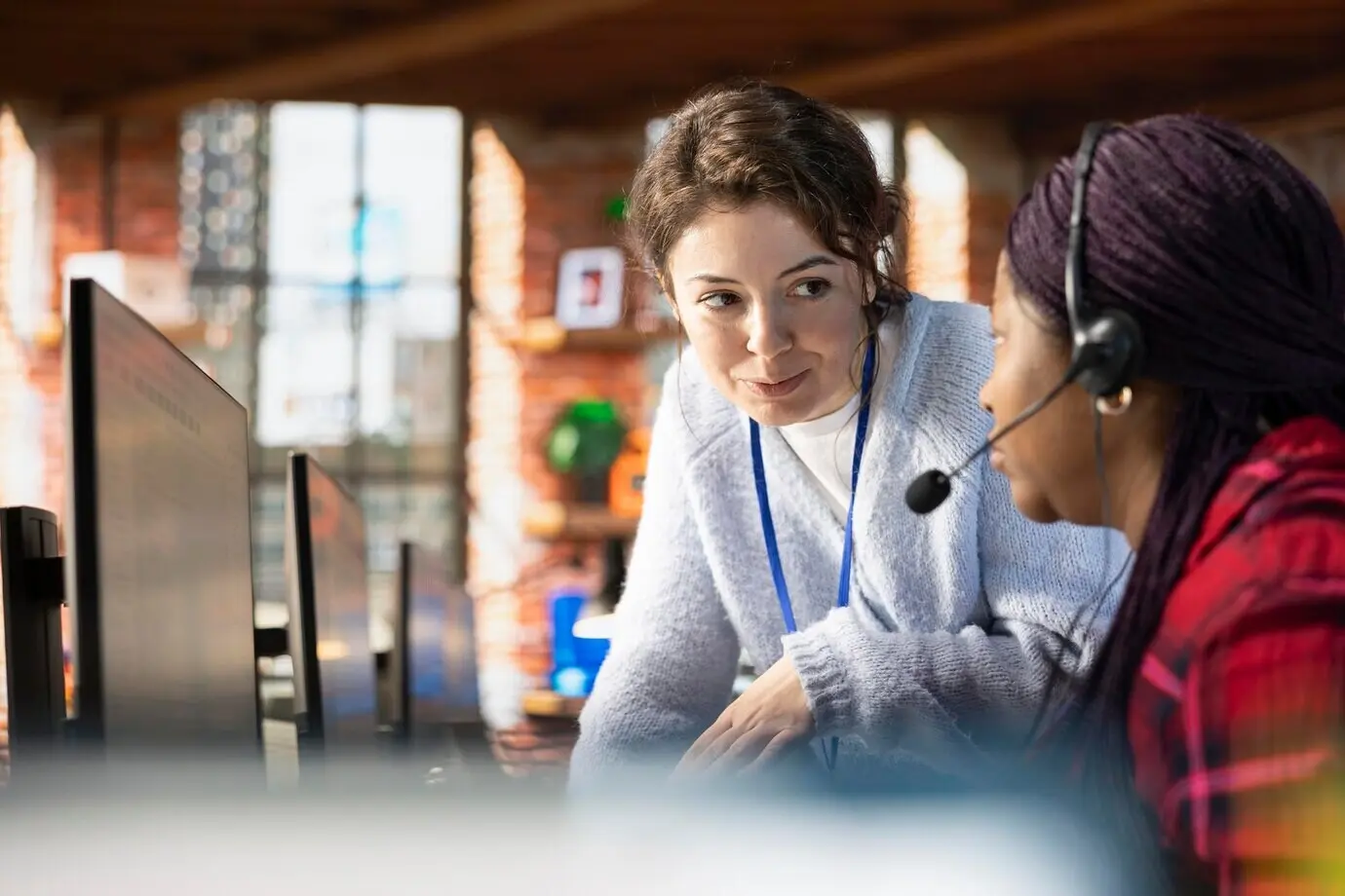 Улыбающийся менеджер колл-центра дает наставления стажёру, отвечающему на вопросы.